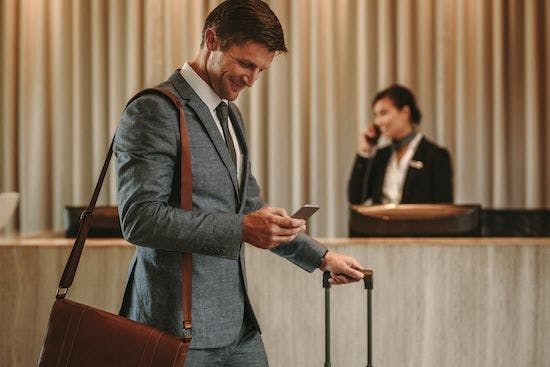 Person with suitcase checking his travel expenses through mobile phone